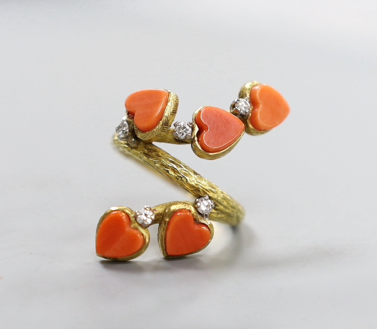 A 1970's modernist 18ct gold, five stone heart shaped coral and five stone diamond set dress ring, maker's mark, LAB, size L/M, gross weight 7.8 grams.